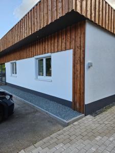 a building with two white garage doors and a wooden wall at Apartment Traumzeit - ebenerdige Wohnung in Gifhorn - Kästorf in Kästorf