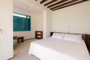 um quarto com uma cama branca e uma janela em Casa Tinti Hotel Boutique em Tintipan Island