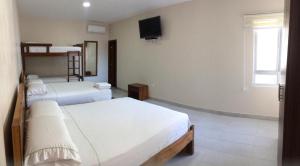 Zimmer mit 3 Betten und einem TV an der Wand in der Unterkunft Hotel Arena Blanca in Salinas