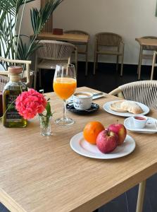 uma mesa de madeira com fruta e um copo de sumo de laranja em Hotel Infanta Leonor em Écija