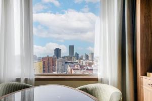 マドリードにあるAC ホテル クスコ ア マリオット ライフスタイル ホテルのテーブルと椅子、大きな窓が備わる客室です。