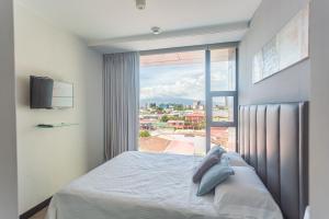 um quarto com uma cama e uma grande janela em Escape to this Rooftop Jacuzzi Apartment em Vuelta del Virilla