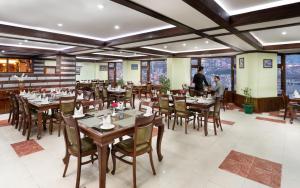 comedor con mesas y sillas de madera en Shobla Royale, en Kulu