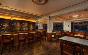 a bar in a restaurant with wooden tables and chairs at Shobla Royale in Kulu