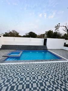 a swimming pool with blue water and a tile floor at Namastay farm in Jaipur