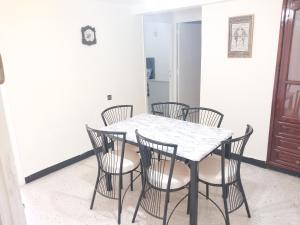une table à manger avec quatre chaises et une table blanche dans l'établissement Superbe appartement à louer,Hassan, à Rabat