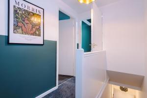 um corredor com paredes azuis e um cartaz emoldurado na parede em Charming 3-Bedroom House-Salford em Manchester