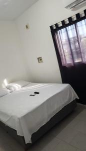 een slaapkamer met een bed met witte lakens en een raam bij Apart Hotel - Eucaliptal in Corrientes