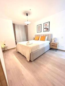 1 dormitorio con 1 cama grande con almohadas de color naranja en Apto. En el Corazón Financiero de Quito-Norte, en Quito