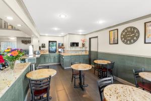 restauracja ze stołami i krzesłami oraz zegarem na ścianie w obiekcie GuestHouse Inn & Suites Kelso/Longview w mieście Kelso