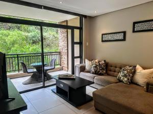 a living room with a couch and a table and a balcony at Resort Retreat, Private Suite, Zimbali Estate in Ballito