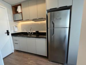 um frigorífico de aço inoxidável numa cozinha com armários brancos em 915 Lux Studio Allianz Park em São Paulo