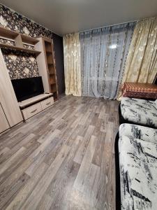 ein Wohnzimmer mit einem Sofa und einem Flachbild-TV in der Unterkunft Назарбаева 204 in Pawlodar