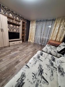 ein Wohnzimmer mit einem Bett und einem TV in der Unterkunft Назарбаева 204 in Pawlodar