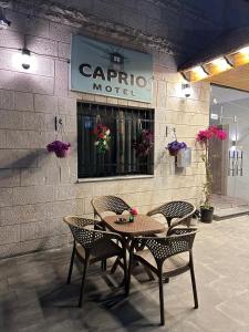 a patio with a table and chairs and a sign at Caprios motel in Al Qasţal
