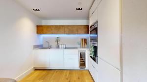una cocina con armarios blancos y fregadero en Luxury apartment in Central London with balcony, en Londres