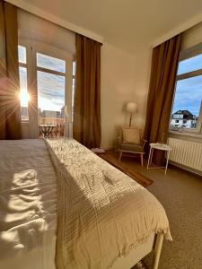 ein Schlafzimmer mit einem Bett, einem Fenster und einem Stuhl in der Unterkunft Hotel Villa Klasen in Wenningstedt-Braderup