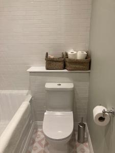 a bathroom with a toilet and a bath tub with baskets at Lovely 1-bedroom flat in Wimbledon in London