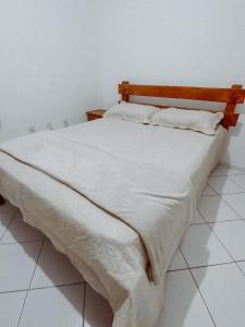 1 cama con sábanas blancas y cabecero de madera en Condomio Coqueiros Residence en Salvador