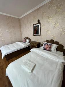 Habitación de hotel con 2 camas con sábanas blancas en 阿拉木图陶萨马勒民宿, en Almaty
