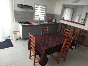 una cucina con tavolo e sedie e una cucina con lavandino di Kaz MADO - Meublé de tourisme - a Le Tampon