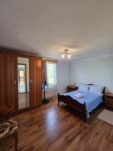 een slaapkamer met een groot bed en houten vloeren bij Blue Guest House in Samtredia
