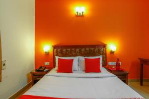 a bedroom with orange walls and a bed with red pillows at Collection O Mamieyaar Veedu in Chennai