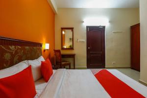 チェンナイにあるCollection O Mamieyaar Veeduの赤い枕のベッドが備わるホテルルームです。