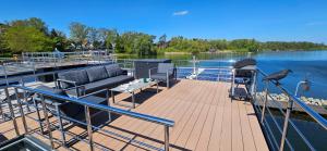 a boat deck with a bench and chairs on the water at Modernes festliegendes Hausboot mit großzügiger Dachterrasse und Ruderboot in Röbel