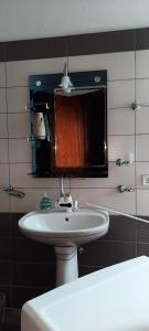 ein Badezimmer mit einem weißen Waschbecken und einem Spiegel in der Unterkunft Fjori's Apartment in Korçë