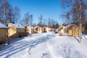 a snow covered street with a row of houses at Nallikari Holiday Village Cottages in Oulu