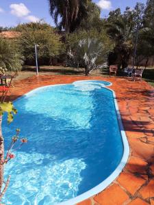 Una gran piscina azul en un patio de ladrillos rojos en Lazer e descaso familiar, en Senador Canedo