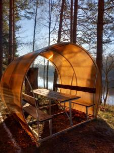 a circular tent with a bench in the woods at UPES 19 in Cēsis