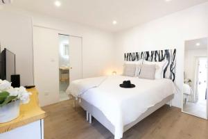 a white bedroom with a large white bed and a mirror at Studio à 200m de la plage de Tahiti beach et à proximité du centre de St Tropez in Saint-Tropez