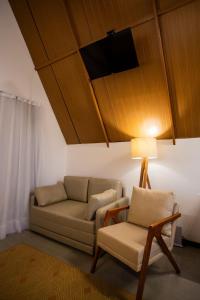 een woonkamer met een bank en een stoel bij Cabana Pitomba - Viagem Inspirada in Fernando de Noronha
