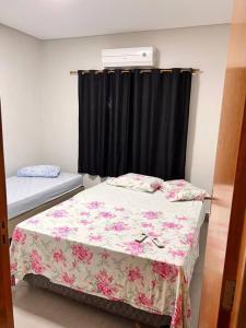 Schlafzimmer mit einem Bett und einem Fenster mit schwarzen Vorhängen in der Unterkunft Casa em Campo Grande com piscina in Campo Grande