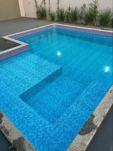 a large swimming pool with blue tiles on the ground at Casa em Campo Grande com piscina in Campo Grande