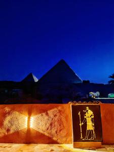 a sign in front of the pyramids at night at Energy Of Pyramid Hotel in Cairo