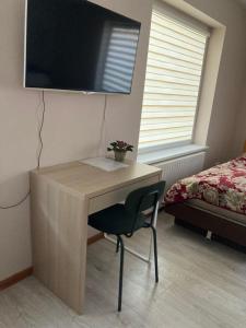 a desk with a chair and a television on a wall at Širvėnos namai - penkiavietis numeris in Biržai
