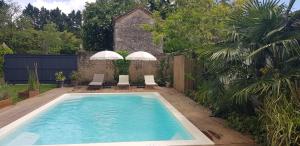 a swimming pool with two umbrellas and two chairs at La maison Malabar in Villefranche-du-Queyran