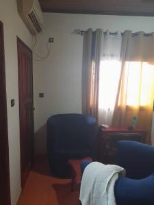 un salon avec une chaise bleue et une fenêtre dans l'établissement Coubaahala, à Yaoundé