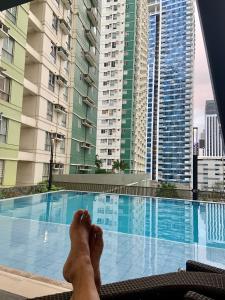 a person laying on a chair next to a swimming pool at Cozy on the 28th! IT Park Cebu City in Cebu City