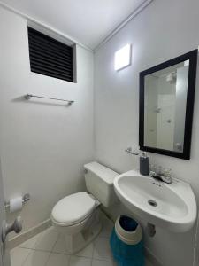 a white bathroom with a toilet and a sink at Apartamento 202 in Itagüí