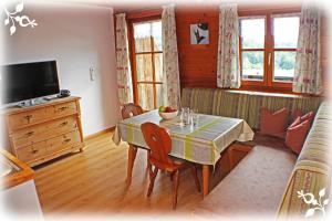 a living room with a dining room table and a television at Ferienwohnungen Lenzenlehen in Marktschellenberg