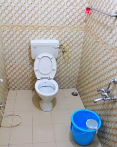 a bathroom with a toilet and a blue bucket at Ooty AR Residency in Ooty