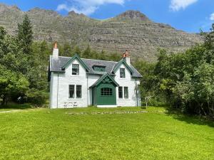 a white house with a mountain in the background at Glen Cottage - Torridon in Achnasheen
