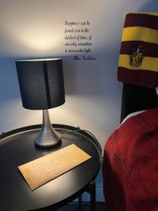 a lamp on a table next to a bed at Potters Escape- Warner Bros Studios & London in Leavesden Green