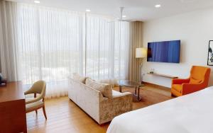 Rendezvous BeachにあるAurora Anguilla Resort & Golf Clubのベッド、ソファ、椅子が備わるホテルルームです。