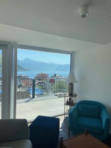 a living room with a blue chair and a large window at Das Anton in Gmunden +3 photos