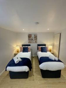 a bedroom with two beds with blue and white sheets at Cosy House Accommodation in Cheltenham